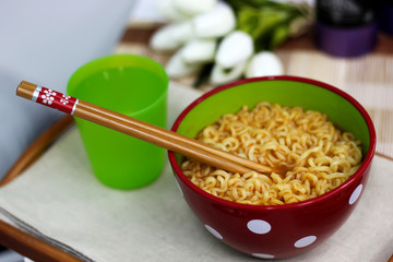 Korean noodles (Ramyun) in red bowl on table