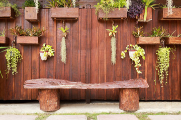 Brown wood wall decorated with variety flowers potted and benches at front, House decoration concept