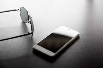 Soft focus smartphones with sunglasses on table for background