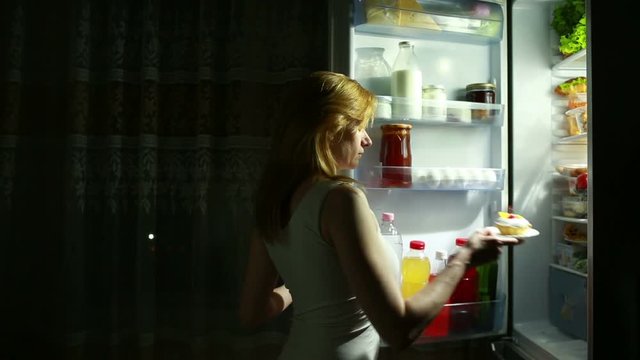 Woman opens the refrigerator at night. night hunger. diet. gluttony