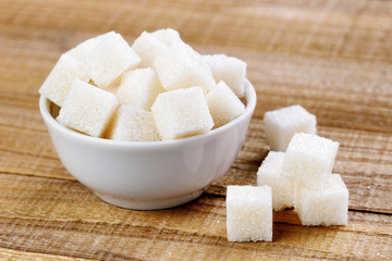 White sugar cubes in bowl on wooden table
