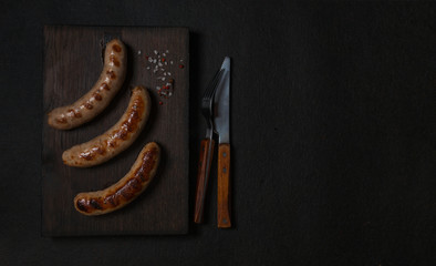 grilled sausages on a dark wooden board top view