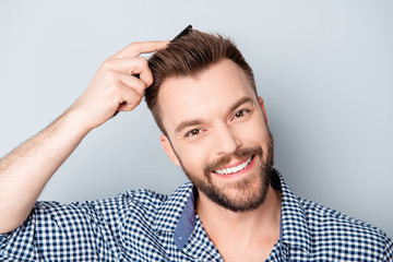 Handsome happy young man combing his hair