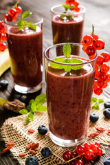  Fresh juicy smoothies with red currants, blueberry, banana, goji berries and chia seeds in a glass jar