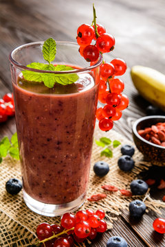  Fresh juicy smoothies with red currants, blueberry, banana, goji berries and chia seeds in a glass jar