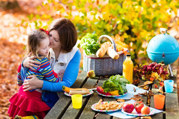 Mother and daughter set table for picnic in autumn