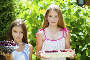 Two little girls with cherries and raspberries