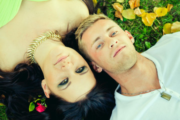 Attractive the guy with the girl lie on a grass closeup