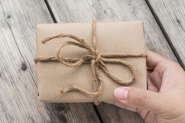 Hands hold A Vintage gift box brown paper wrapped with rope on w