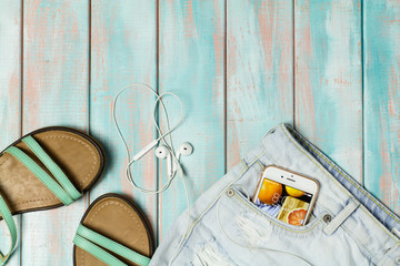 Sandals, headphones and accessories, set out for a walk on a rustic wooden background