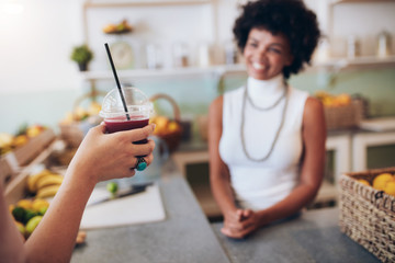 Glass of fresh fruit juice in hand of a customer