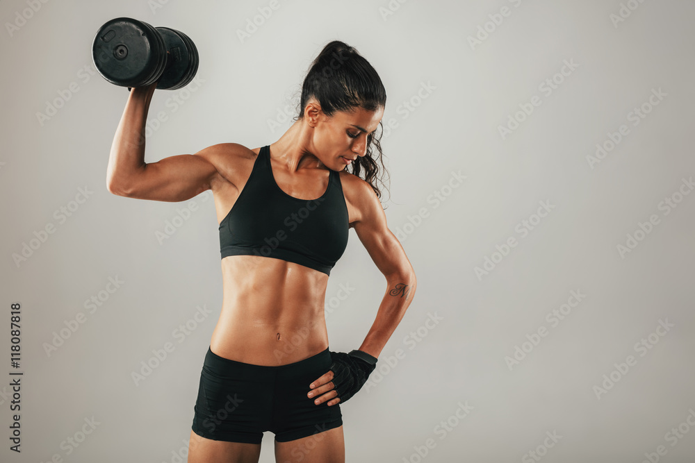 Wall mural Toned muscular young woman working out