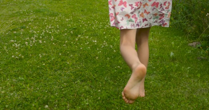 Camera following sweet girl in pink dress running away in the garden