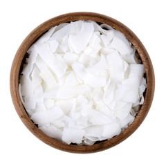 Coconut flakes in a bowl on white background, also called copra. Dried and grated flesh or meat of...
