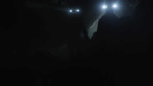 Explorer Silhouettes walking through dark cave