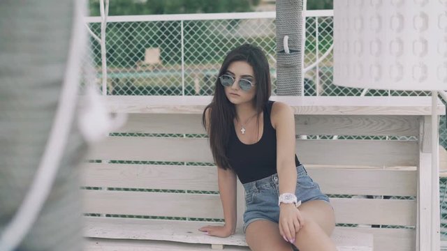 Pretty girl relaxing on a bech bench overlooking the beach in 4K