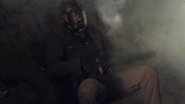 The war against cyborgs. A man in a black gas mask shoots a machine gun being in a trench. Montage.