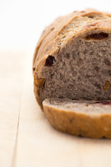 whole grain bread with dried cranberry and walnut. only one slice cut on a cutting board. vertical