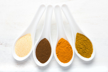 variety of spices in white spoons, overhead view
