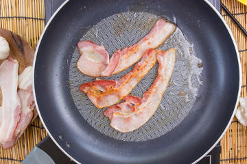 Chef frying bacon in the pan