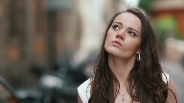 Forward shot of young serious and attractive woman walking on city street with beautiful flower bouquet