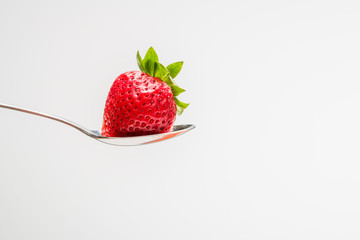 Strawberry in a spoon with a white background. With room for tex