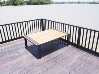 Wooden table on wooden terrace near the river