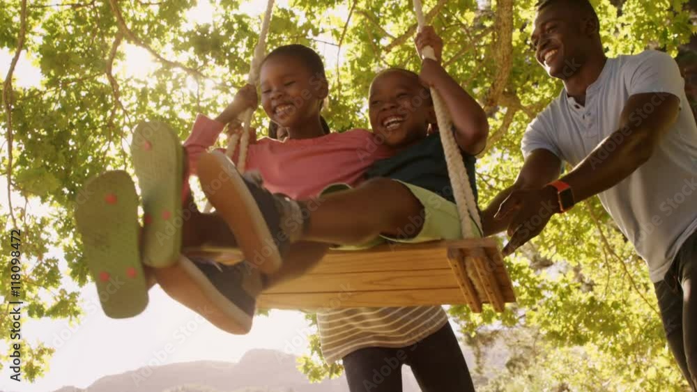 Poster low angle view of happy family playing on the swings