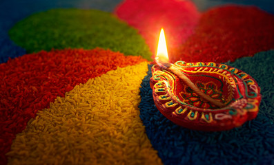 Diwali oil lamp - Diya lamp lit on colorful rangoli - obrazy, fototapety, plakaty