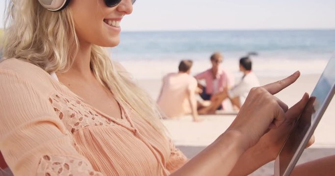 Woman lying on her deckchair with her tablet at beach 