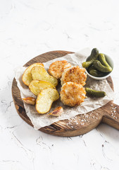 Fish balls and baked potatoes on wooden cutting board on white background