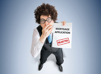 Disappointed businessman is showing paper with denied mortgage application.