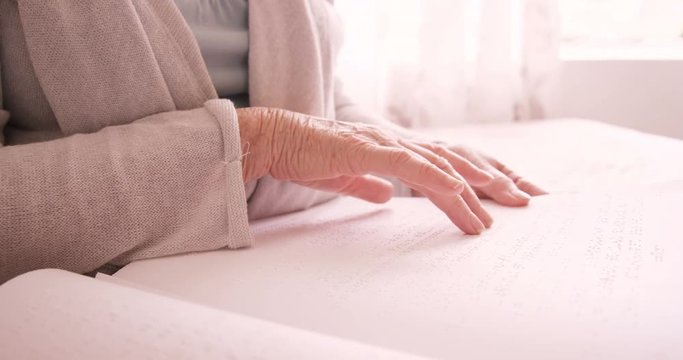 Senior blind man reading a braille book