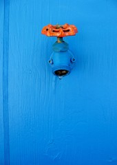 Closeup faucet on blue wall background. Tap closeup with dripping water-drop.