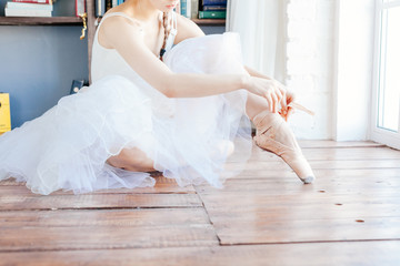 Fototapeta na wymiar Ballet dancer tying slippers around her ankle woman ballerina pointe