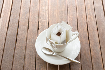 Coffee cup with packaged coffee on wooded table