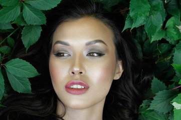 Fototapeta premium Girl lying in the green foliage