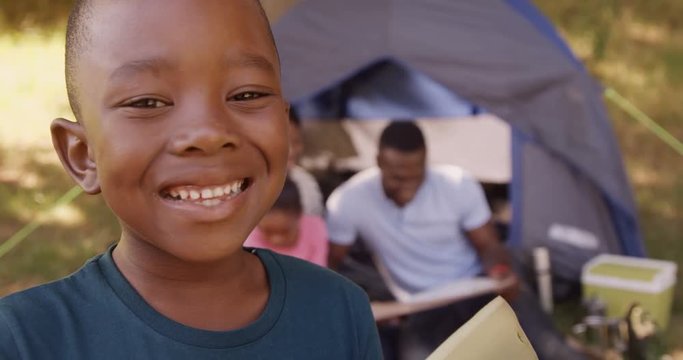 Child smiling at camera in front of a tent