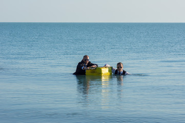 Businessmen on a yellow suitcase floating in the sea