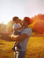 Happy father holding on hands child son warm autumn evening, sun