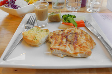pork steak with vegetable on a plate and wooden table background