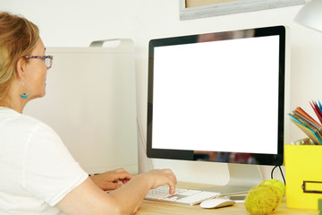 Back view of beautiful mature female wearing white T-shirt using PC with blank copy space screen for your promotional text or advertising content, paying household bills online, checking e-mail
