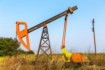 Fototapeta na wymiar A small private oil derrick pumps oil on the field. 