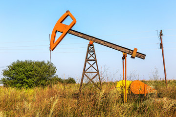 Fototapeta na wymiar A small private oil derrick pumps oil on the field. 