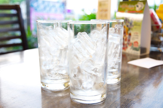 Ice in the glasses placed on wooden table,focus front glass.