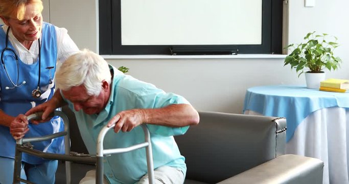 Nurse helping retired man with walker in retirement home