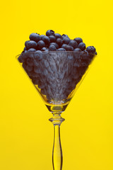 Non-alcoholic drinks concept. Fresh blueberries in shining conic glass