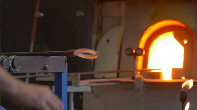 the Man Imparts a Round Form to the Glass Decoration With Help of Metal Tools