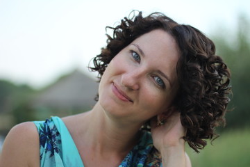 portrait of a smiling young woman with dark curly short hair