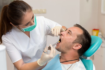 Dentist giving an injection of anesthesia to the patient. Young man at the dental clinic